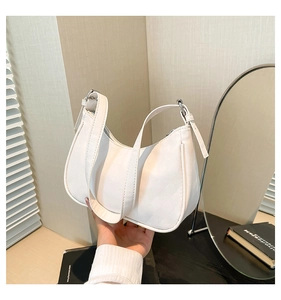 Detail of white crescent shoulder bag featuring diamond lattice texture and metal buckle