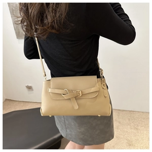 Vue détaillée du sac beige avec design à nœud et pieds de protection en métal au fond