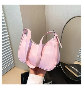 Detail of pink crescent bag showing diamond-quilted texture and shoulder strap hardware