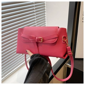 Detail of rose red leather crossbody bag with gold hardware and buckle flap closure