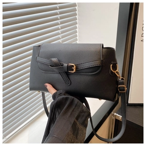 Detail of black PU leather handbag featuring decorative knotted strap and gold buckle