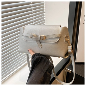 Close-up of silver-gray textured crossbody bag with bow detail and gold hardware