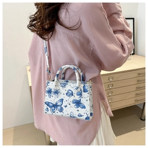 Detail of white butterfly print tote bag showing the pattern and adjustable shoulder strap