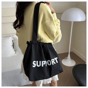 Close-up of black canvas tote bag with white SUPPORT text print and durable shoulder strap