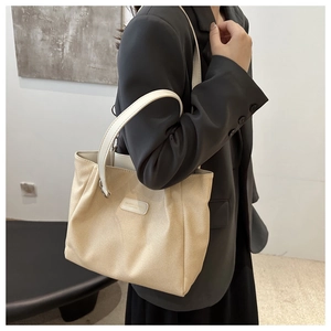 Close-up of textured fabric tote bag on model's shoulder showing minimalist design details