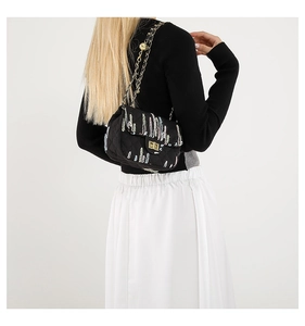 Detail of black quilted crossbody bag with colorful embroidery and golden metal lock