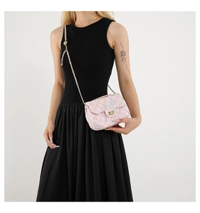 Detail of pink quilted crossbody bag with gold chain strap and metal turn-lock closure