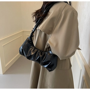 Détail du sac sous les aisselles plissé noir porté avec un trench-coat kaki élégant