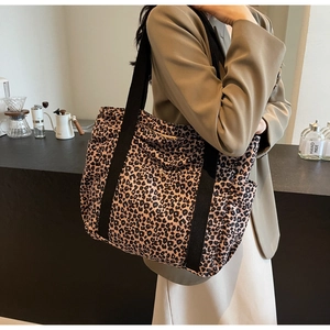 Detailed view of leopard print tote bag with black wide straps held by a model