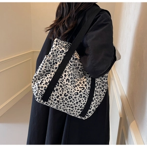 Detail view of large leopard print tote bag with black straps on model's shoulder