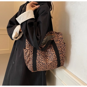 Detail of leopard print tote bag with black straps and side functional pockets