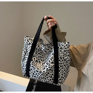 Detail of leopard print tote bag featuring wide black straps and side pocket functionality