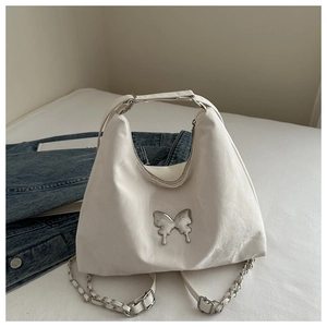 Detail of white textured shoulder bag featuring a silver butterfly buckle and chain strap