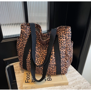 Close-up of leopard print tote bag with black webbing straps and side pocket detail
