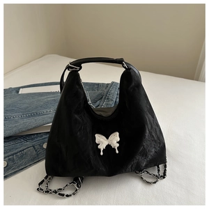 Detail of black textured hobo bag featuring a silver liquid metal butterfly hardware buckle