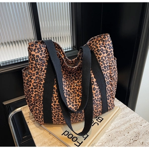 Detailed side view of leopard print tote bag with wide black straps and side pocket
