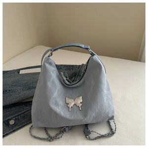 Detail of light blue pleated tote with a silver metallic butterfly buckle and chain strap