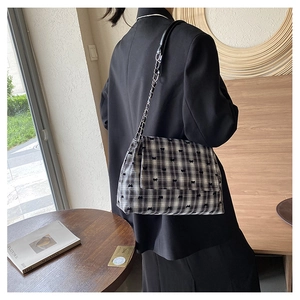 Détail latéral d'un sac à bandoulière à carreaux avec petits nœuds sur un mannequin