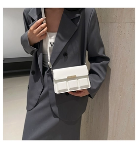 Detail of matte white crossbody bag with 3D square design on a grey suit model