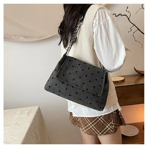 Close-up of a grey polka dot shoulder bag with butterfly embroidery and chain strap