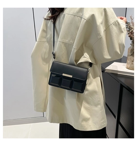 Detail of black leather crossbody bag featuring unique chocolate texture and metal buckle