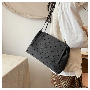 Détail d'un sac cabas gris foncé à pois avec bandoulière chaîne porté par un mannequin