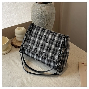 Détail du sac à bandoulière à carreaux noir et blanc avec petits nœuds et chaîne