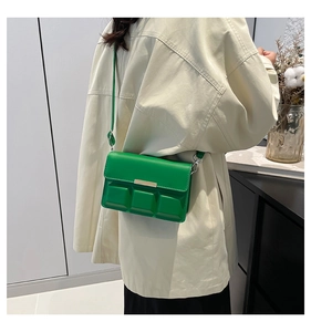 Side view of model wearing a bright green crossbody square bag with relief texture