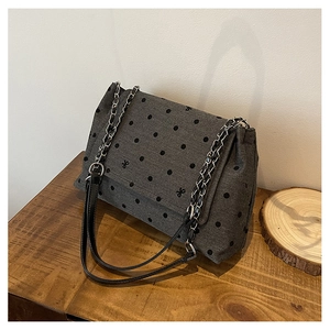 Détail du sac gris à pois noirs avec broderie nœud et bandoulière en chaîne argentée