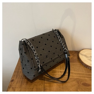 Détail du sac en tissu gris foncé à pois avec petits nœuds et bandoulière en chaîne