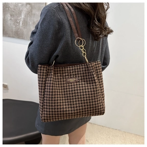 Detail of houndstooth fabric texture with leather strap and gold chain on tote bag
