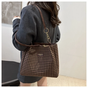 Classic houndstooth tote bag on model's shoulder with gold chain and leather strap