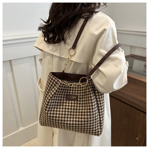 Detail of vintage houndstooth tote bag featuring leather straps and golden chain link