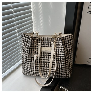 Detail of houndstooth fabric texture and metal chain strap on this stylish tote bag