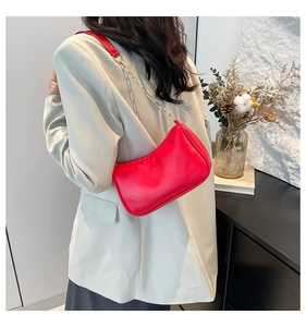 Detail of red leather shoulder bag with gold chain strap on beige blazer outfit