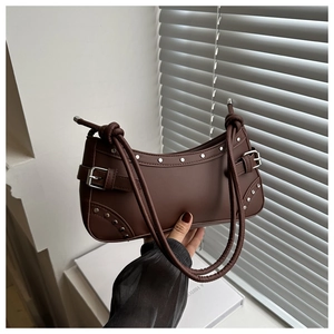 Dettaglio borsa baguette marrone scuro con borchie argentate e fibbie decorative laterali