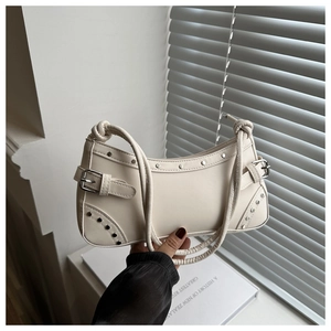 Dettaglio della borsa hobo retrò bianco sporco con rivetti argento e tracolla annodata