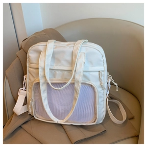 Dettaglio della borsa tote in nylon crema con tasca a rete su una poltrona in pelle