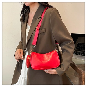 Detail of red baguette bag with adjustable strap and coin purse worn by a model