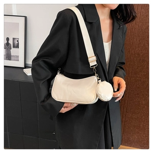 Detail view of cream-colored crescent bag with adjustable wide strap and coin pouch accessory
