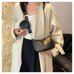 Detail of black leather crossbody bag with small round pouch and wide textile shoulder strap