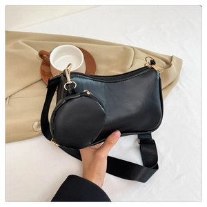 Detail of black faux leather baguette bag with detachable round coin purse and gold hardware