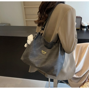 Vue détaillée du sac cabas gris mat avec étiquette de marque et porte-clés ours