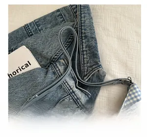 Close-up of blue gingham tote bag with slim handles and denim jacket background