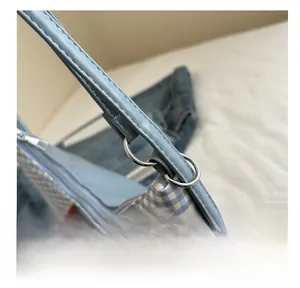 Close-up of gingham tote bag featuring blue embroidery and premium silver hardware details