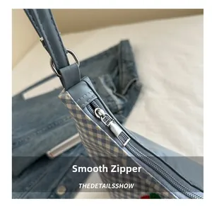 Detailed close-up of the smooth silver zipper on a light blue checkered tote bag