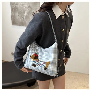 Detailed close-up of blue gingham shoulder bag with cartoon dachshund embroidery