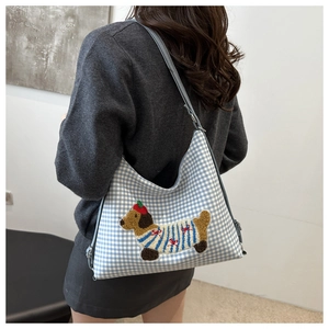 Close-up of blue gingham fabric with cartoon dachshund embroidery on the hobo bag