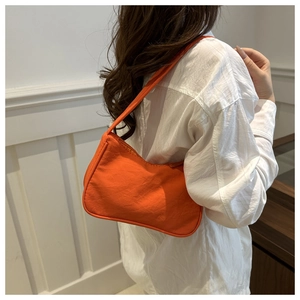 Bright orange nylon underarm bag with zipper closure shown on a model in a white room