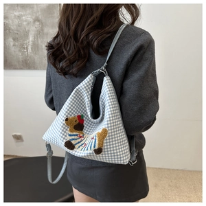 Detail of blue and white checkered bag featuring cute embroidered cartoon dog patch